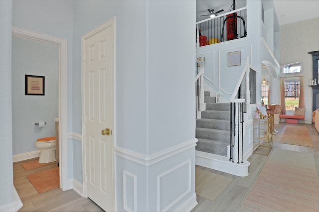 stairway with hardwood / wood-style floors and ceiling fan