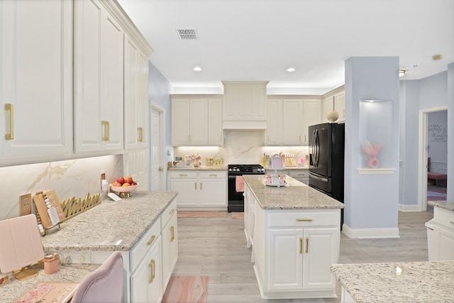 kitchen featuring black appliances, light stone countertops, backsplash, and light hardwood / wood-style flooring