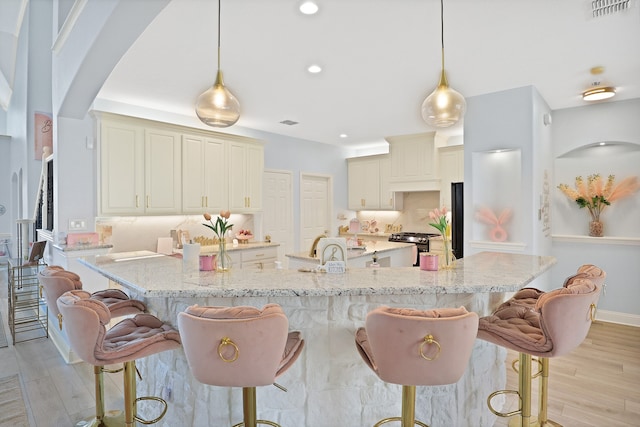 kitchen featuring light stone countertops, light hardwood / wood-style flooring, and hanging light fixtures