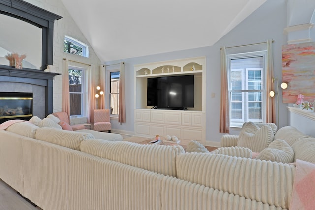 living room with hardwood / wood-style floors, built in shelves, lofted ceiling, and a wealth of natural light