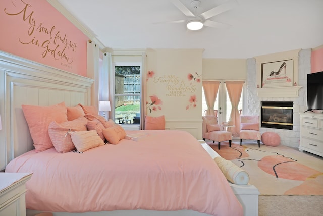 carpeted bedroom with ceiling fan, a large fireplace, ornamental molding, and french doors