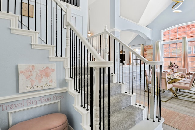 stairs with wood-type flooring and high vaulted ceiling