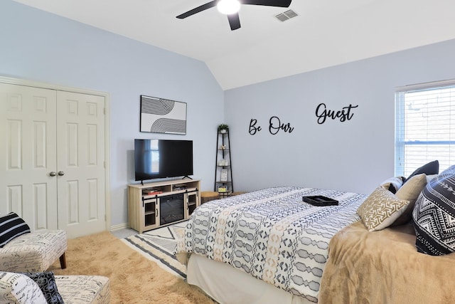 bedroom featuring ceiling fan, a closet, light colored carpet, and vaulted ceiling