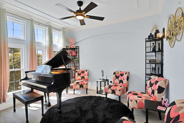 sitting room featuring light wood-type flooring, ceiling fan, and crown molding