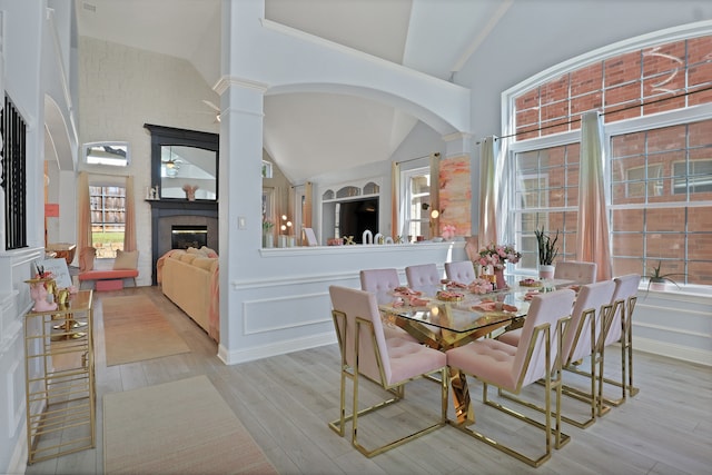 dining room featuring light hardwood / wood-style floors, high vaulted ceiling, and decorative columns