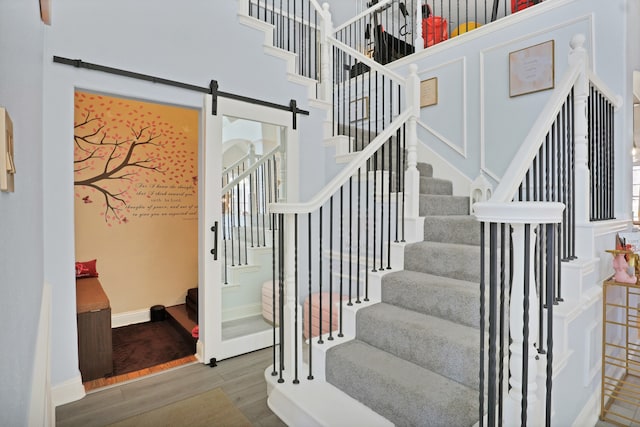 stairs with a barn door and wood-type flooring