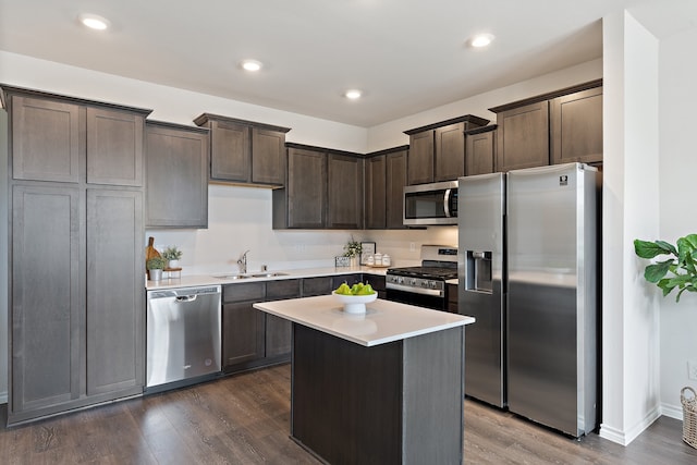 kitchen featuring dark brown cabinets, appliances with stainless steel finishes, sink, dark wood-type flooring, and a center island