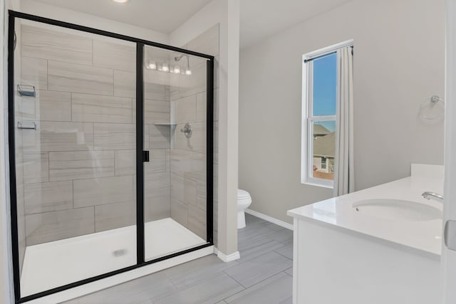 bathroom with vanity, a shower with shower door, and toilet