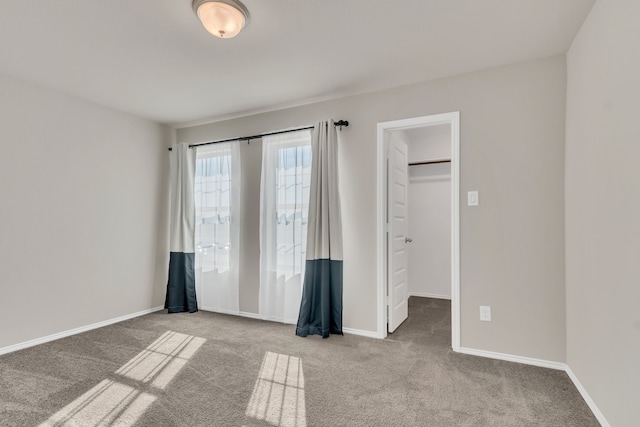 unfurnished bedroom with a spacious closet, a closet, and light colored carpet