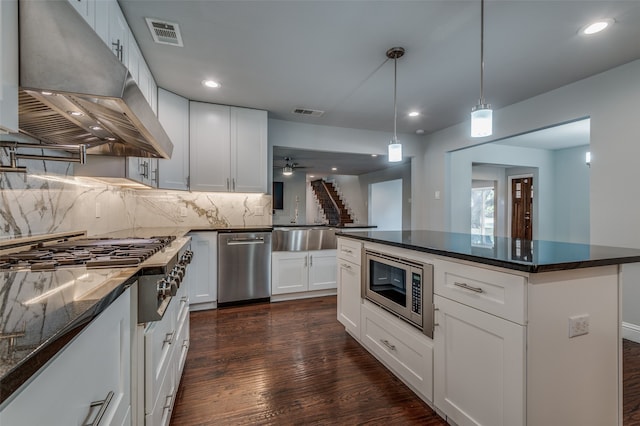 kitchen featuring dark hardwood / wood-style flooring, stainless steel appliances, pendant lighting, white cabinets, and range hood