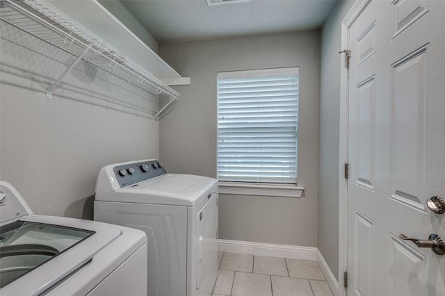 clothes washing area with light tile patterned flooring and washing machine and dryer