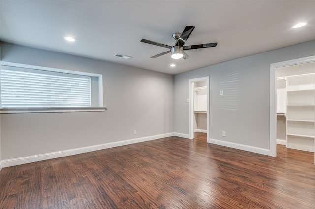 unfurnished bedroom with a closet, ceiling fan, dark hardwood / wood-style flooring, and a walk in closet