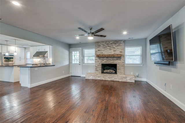 unfurnished living room with ceiling fan, dark hardwood / wood-style floors, and a fireplace