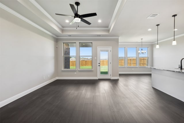 unfurnished living room with a raised ceiling, dark hardwood / wood-style flooring, ceiling fan with notable chandelier, and ornamental molding