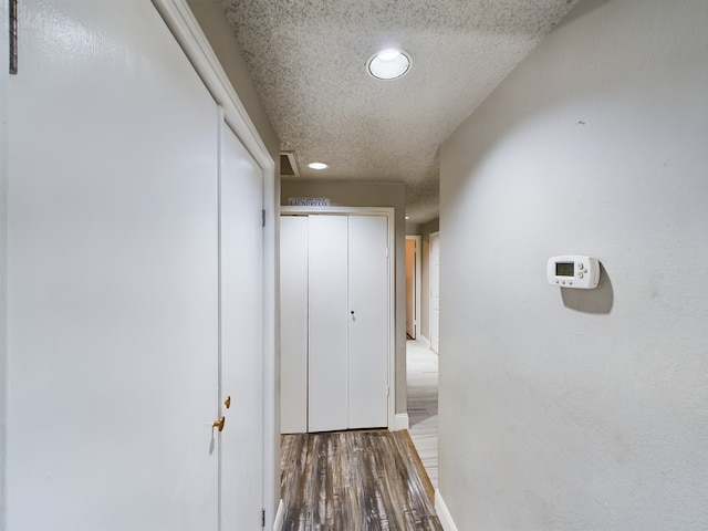 hall featuring a textured ceiling and wood-type flooring