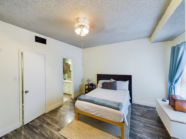 bedroom featuring ceiling fan, dark hardwood / wood-style flooring, ensuite bath, and a textured ceiling