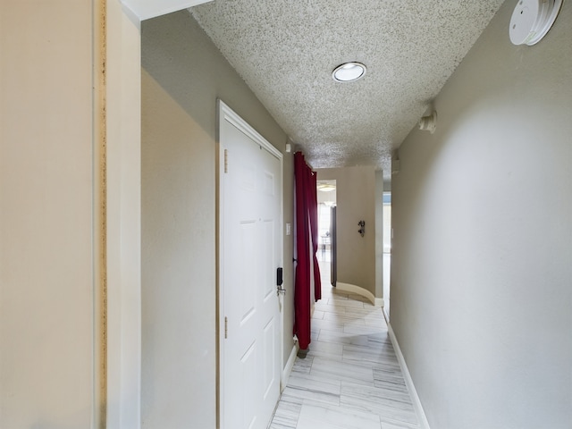 hall featuring a textured ceiling