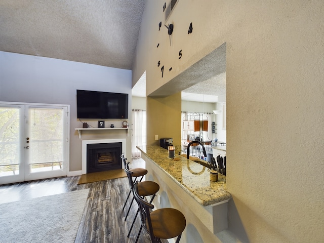 kitchen with a breakfast bar, dark hardwood / wood-style flooring, a wealth of natural light, and light stone countertops