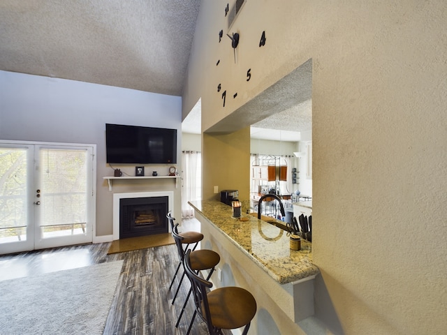 9747 Whitehurst Dr Unit 146, Dallas, TX 75243 - living room with wood finished floors, a textured wall, a fireplace with flush hearth, a textured ceiling, and high vaulted ceiling