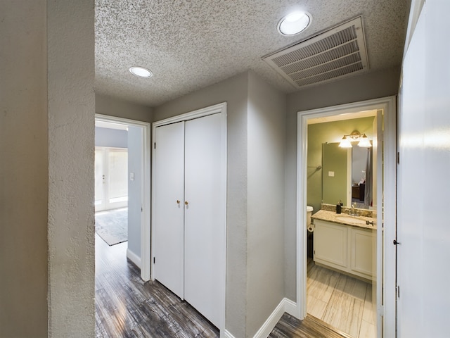 hallway featuring a textured ceiling, dark hardwood / wood-style flooring, and sink