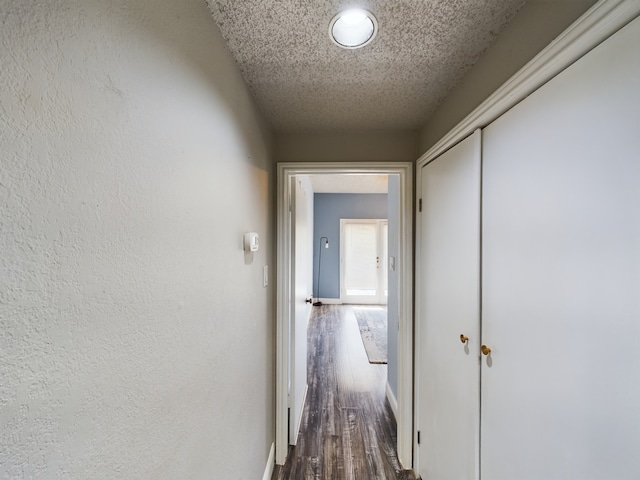 corridor with a textured ceiling and wood-type flooring