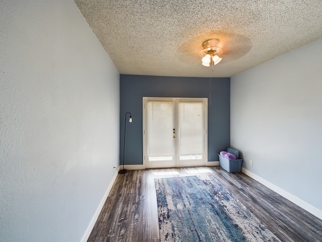 unfurnished room featuring french doors, a textured ceiling, ceiling fan, and dark wood-type flooring