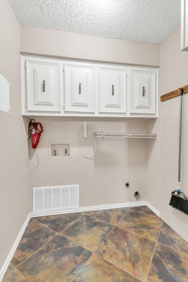 clothes washing area with a textured ceiling, washer hookup, cabinets, and a barn door