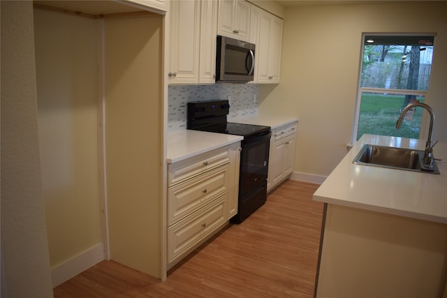 kitchen featuring decorative backsplash, light hardwood / wood-style flooring, sink, black electric range, and white cabinets