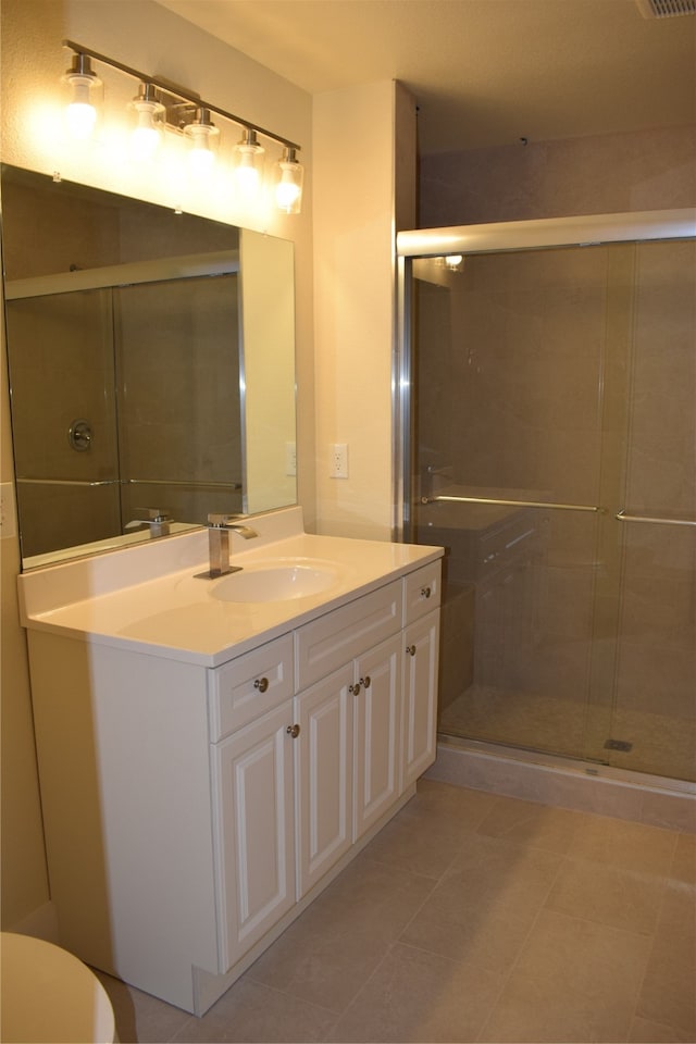 bathroom with vanity, a shower with shower door, toilet, and tile patterned floors