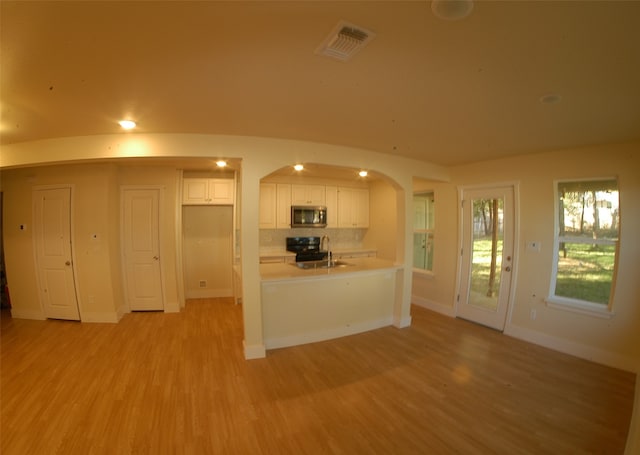 kitchen with decorative backsplash, light hardwood / wood-style flooring, white cabinets, and black electric range oven