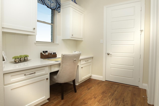 office space with built in desk and dark hardwood / wood-style flooring