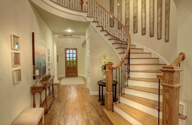 foyer featuring a towering ceiling and wood-type flooring