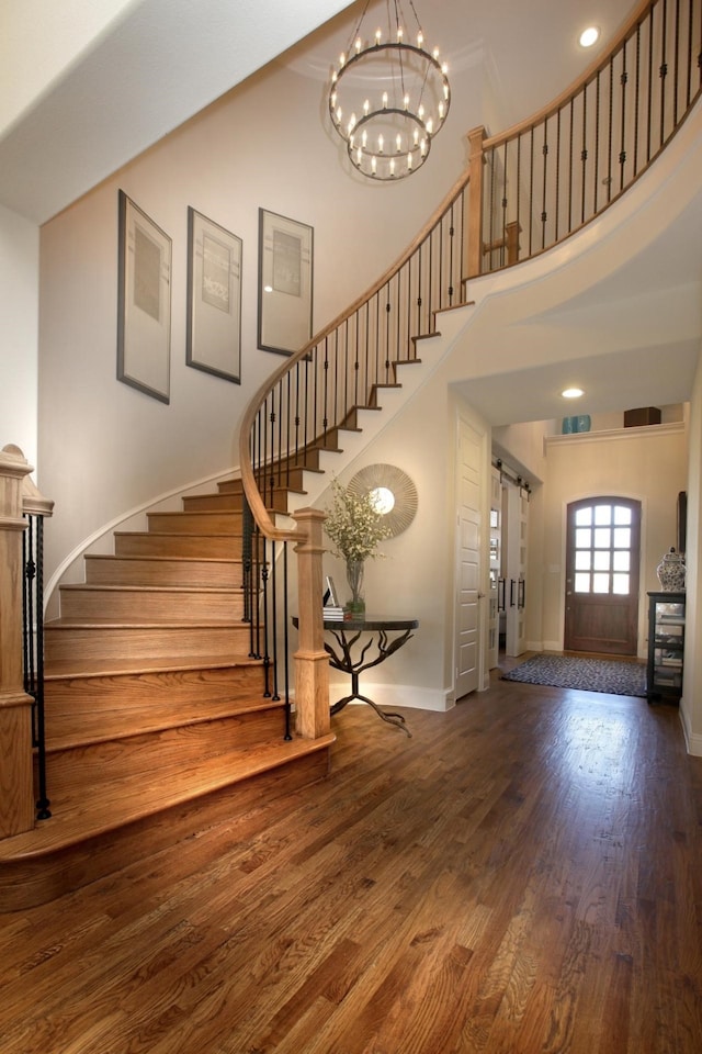 stairway featuring a towering ceiling, ornamental molding, hardwood / wood-style floors, and an inviting chandelier