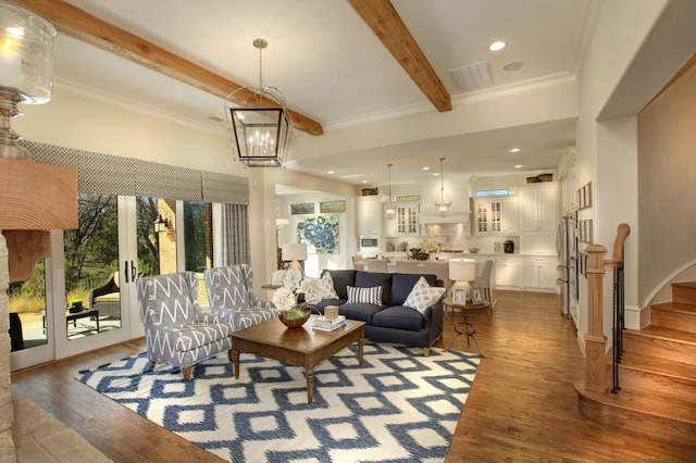 living room featuring a chandelier, wood-type flooring, beamed ceiling, a towering ceiling, and crown molding