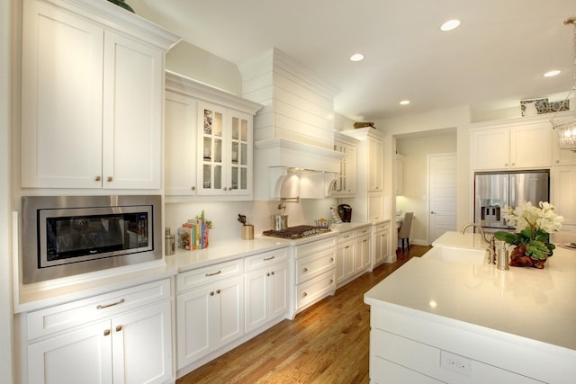 kitchen featuring appliances with stainless steel finishes, decorative light fixtures, light wood-type flooring, and white cabinetry