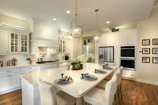 kitchen featuring appliances with stainless steel finishes, an island with sink, dark hardwood / wood-style flooring, hanging light fixtures, and a breakfast bar