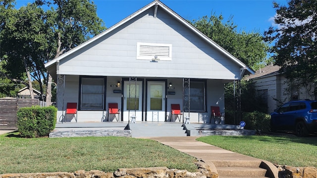 bungalow featuring covered porch and a front lawn