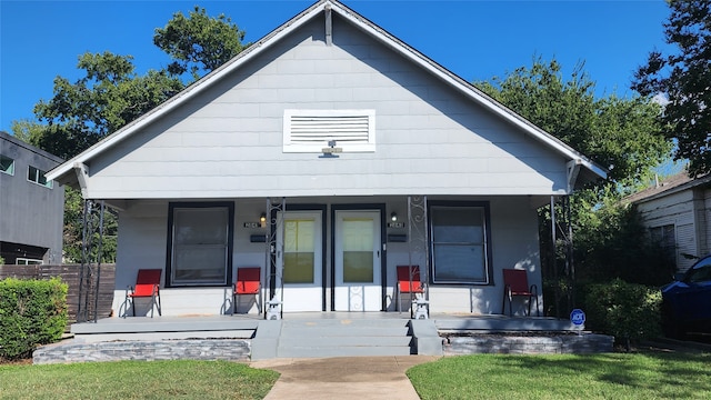 bungalow featuring covered porch and a front lawn