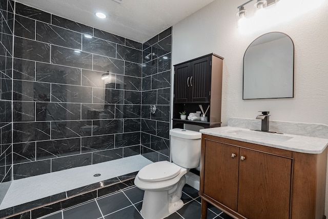 bathroom with vanity, tiled shower, toilet, and tile patterned flooring