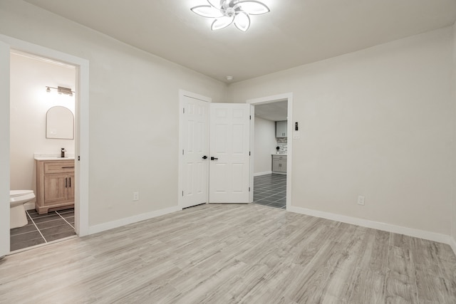 unfurnished bedroom with light hardwood / wood-style flooring, a closet, and connected bathroom