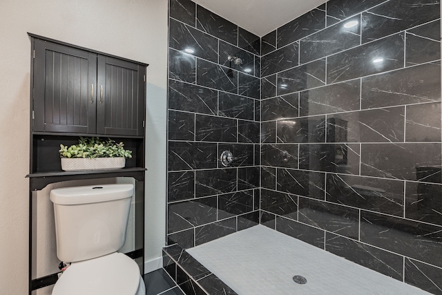 bathroom with a tile shower and toilet