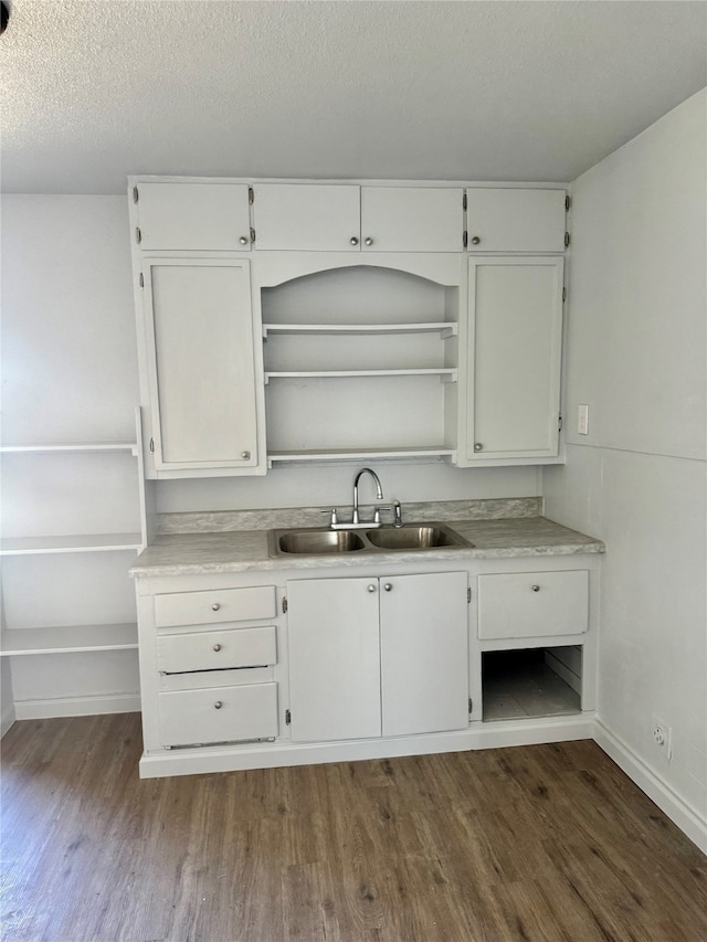 kitchen featuring dark wood-type flooring, a textured ceiling, sink, and white cabinets