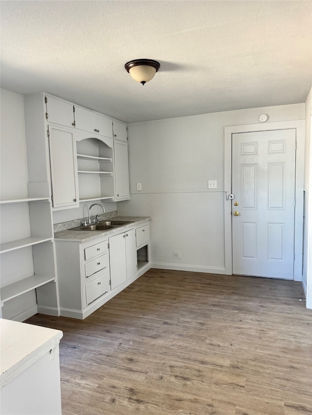 kitchen with sink, white cabinets, a textured ceiling, and light wood-type flooring