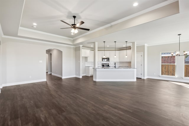 unfurnished living room featuring dark hardwood / wood-style floors, crown molding, and ceiling fan with notable chandelier