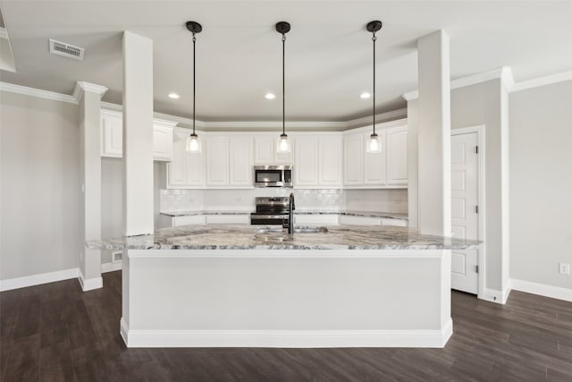 kitchen with backsplash, a center island with sink, appliances with stainless steel finishes, light stone counters, and white cabinetry