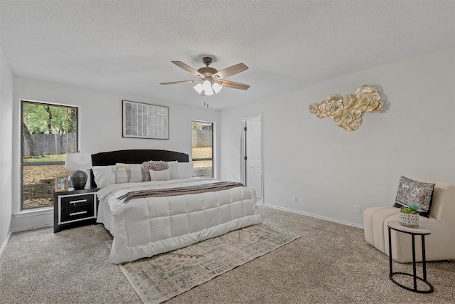 bedroom featuring a textured ceiling, carpet floors, multiple windows, and ceiling fan