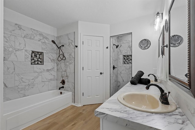 bathroom featuring hardwood / wood-style flooring, vanity, a textured ceiling, and tiled shower / bath combo