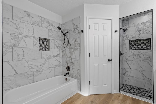 bathroom with hardwood / wood-style floors, a textured ceiling, and tiled shower / bath combo