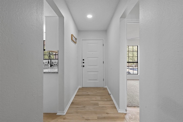 hall featuring a textured ceiling and light wood-type flooring