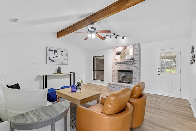 living room featuring hardwood / wood-style floors, lofted ceiling with beams, ceiling fan, and a fireplace